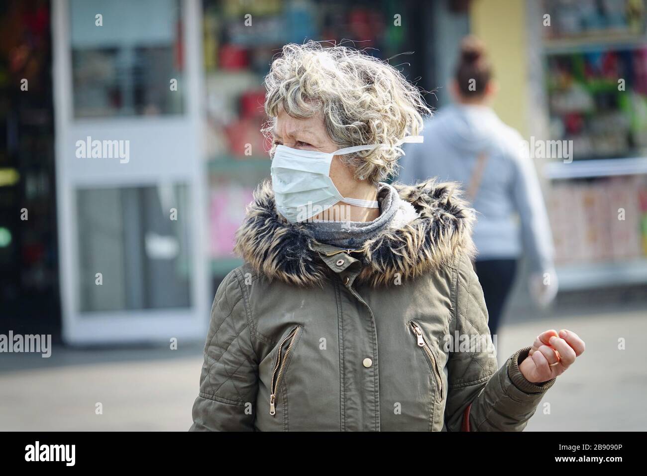 An elderly woman wearing a mask in the market. Selective focus on the face. Milan, Italy - March 2020 Stock Photo