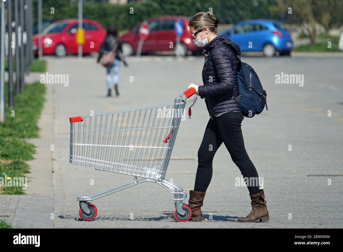 Coronavirus pandemic effects: woman in queue to enter the supermarket for grocery shopping. Milan, Italy - March 2020 Stock Photo