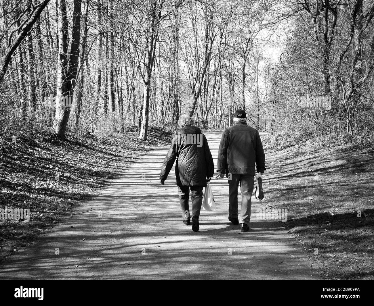 Munich, Bavaria, Germany. 23rd Mar, 2020. A couple goes for a stroll in Munich, Germany displaying the new normal of tge so-called ''Kontaktverbot'', which restricts contacts to a max of two people eho live in the same household. Larger groups will be subject to fines under the Infektionsschutzgesetz in order to stem the spread of Covid-19 (SARS COV 2) via public meeting places. Credit: Sachelle Babbar/ZUMA Wire/Alamy Live News Stock Photo
