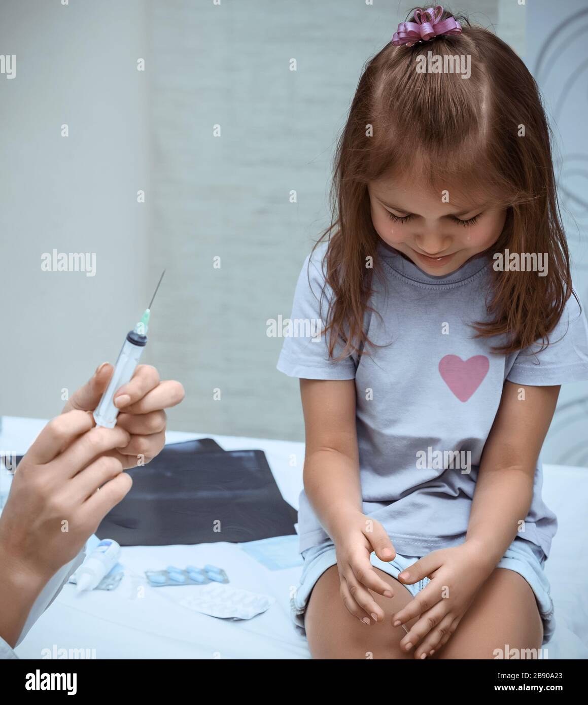 Little girl crying at the doctor's clinic, the kid is scared from vaccination and injection, tears streaming down baby's face, the vaccination Stock Photo