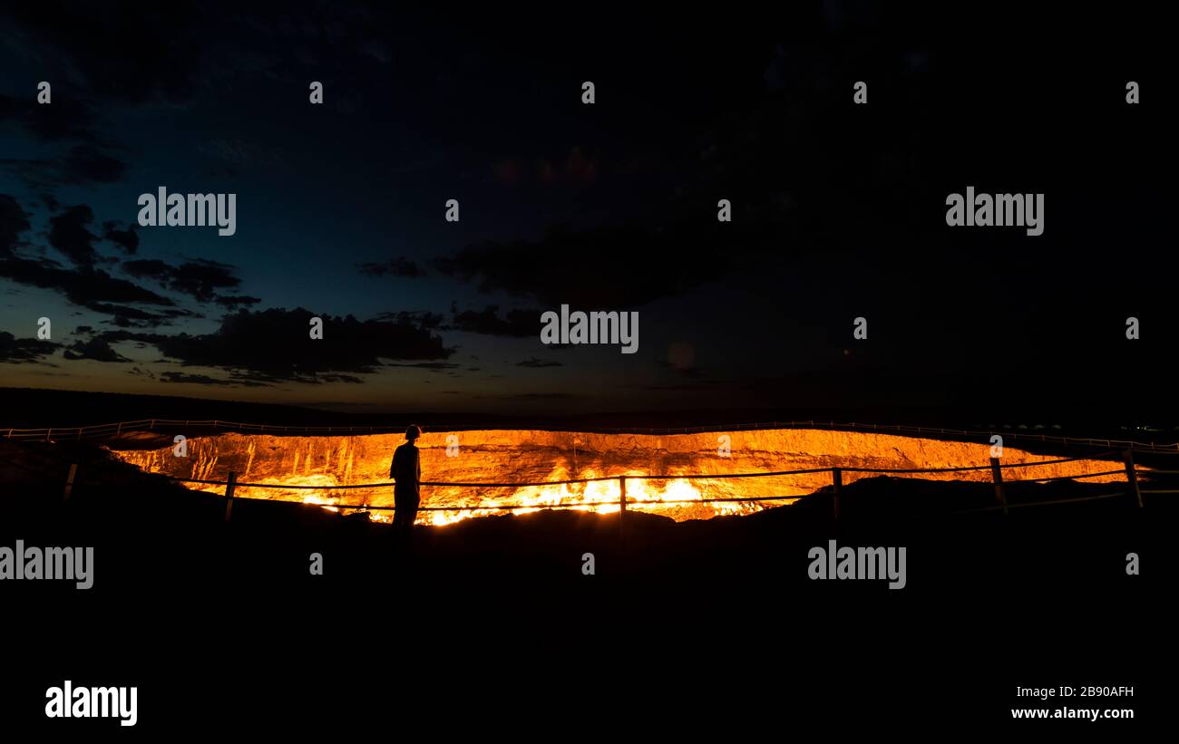 Darwaza, Turkmenistan - June 3 2019: Woman at fire gate to hell of the Darwaza  (Derweze) gas crater in the Karakum Desert in Turkmenistan. Stock Photo
