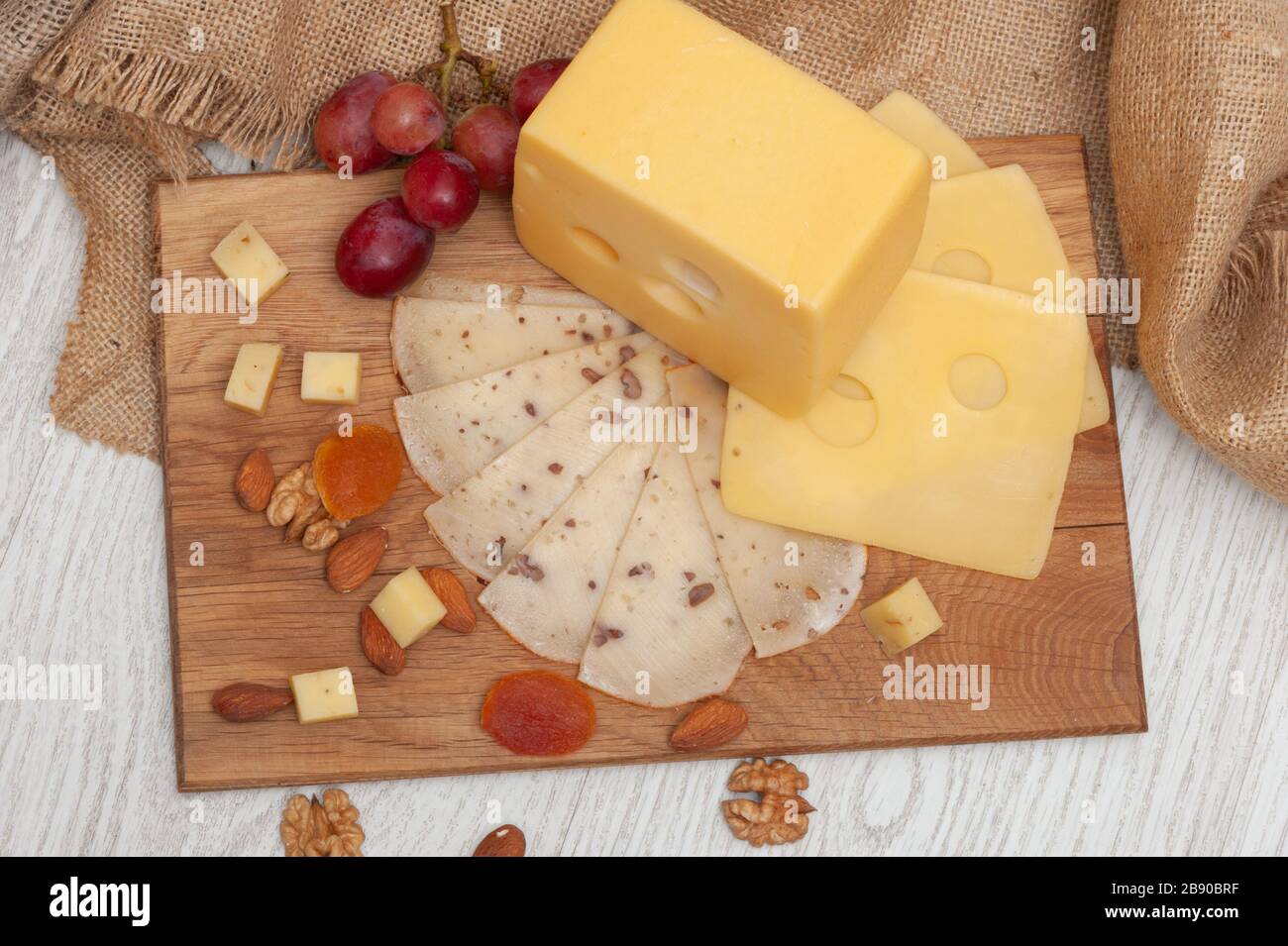 sliced walnut cheese on a board, grapes, dried apricots and nuts Stock
