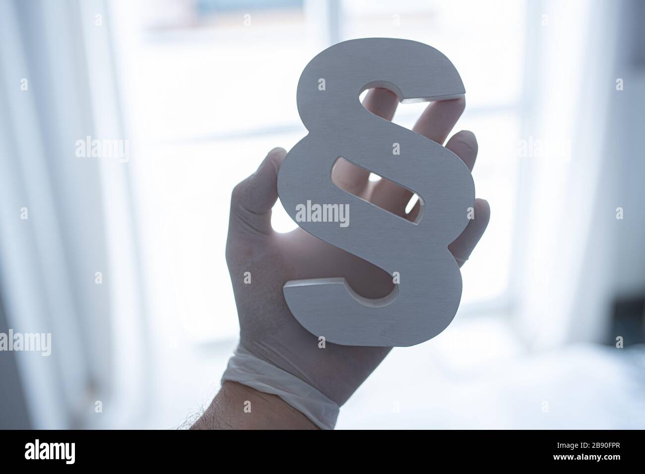 Man wears protective latex gloves and holding paragraph symbol of law