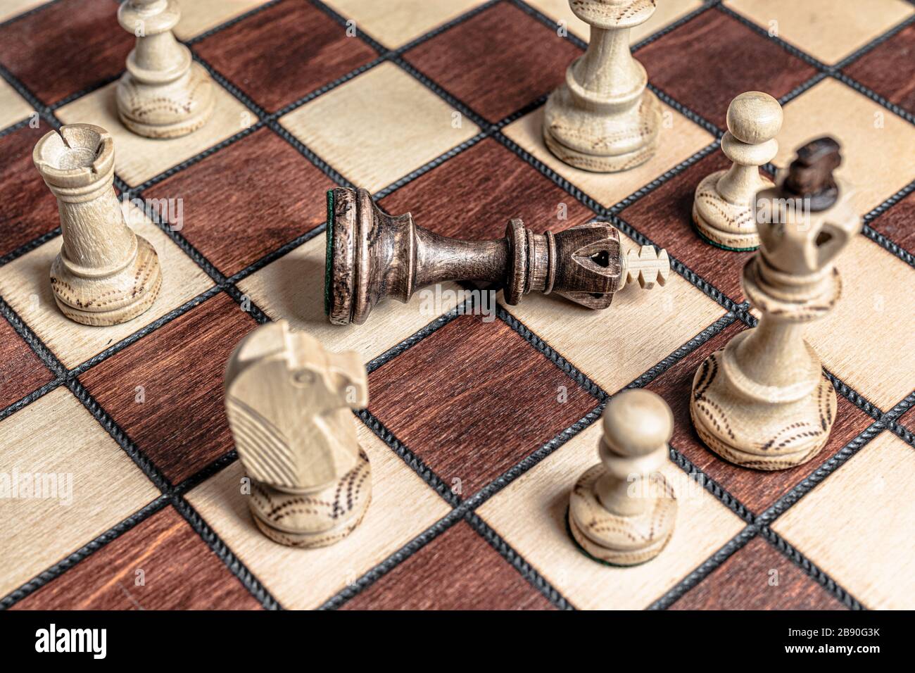 Chess board with black king surrendered to overwhelming force of white chess pieces. Royalty free stock photo. Stock Photo