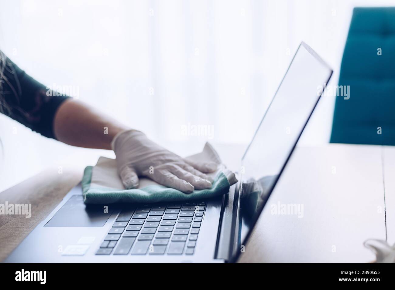 Woman disinfects the laptop keyboard with spray disinfectant liquid