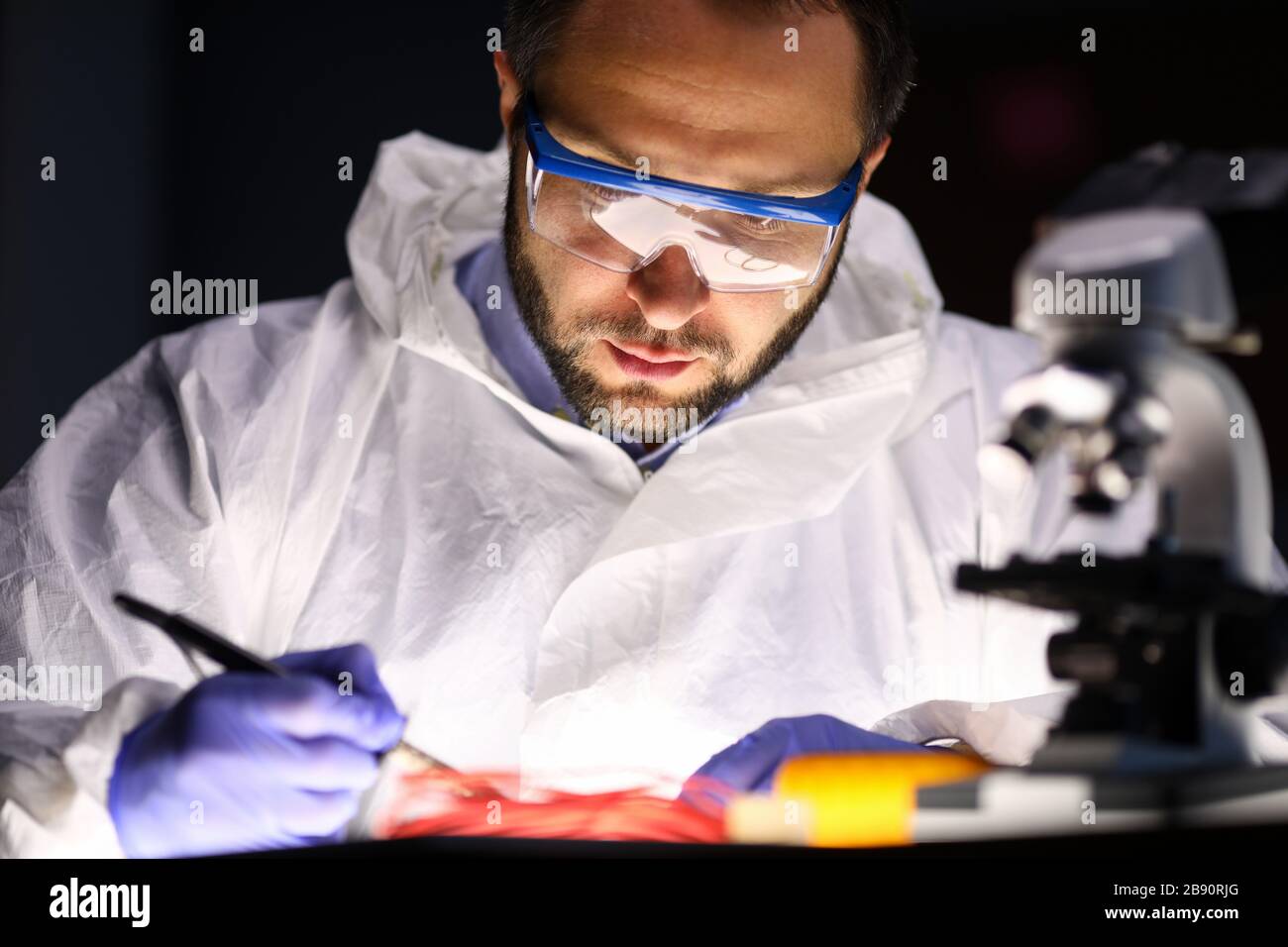 Man laboratory repairs instrument near microscope Stock Photo