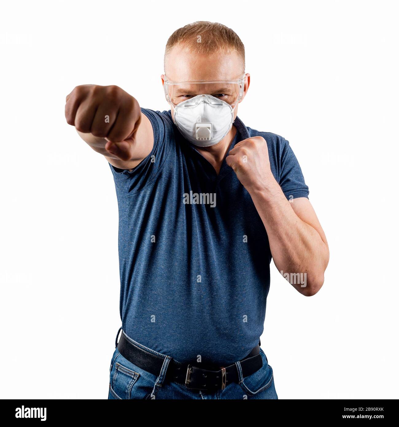 A man in a protective mask and glasses strikes with his fist. The concept of impact on coronavirus. Stock Photo