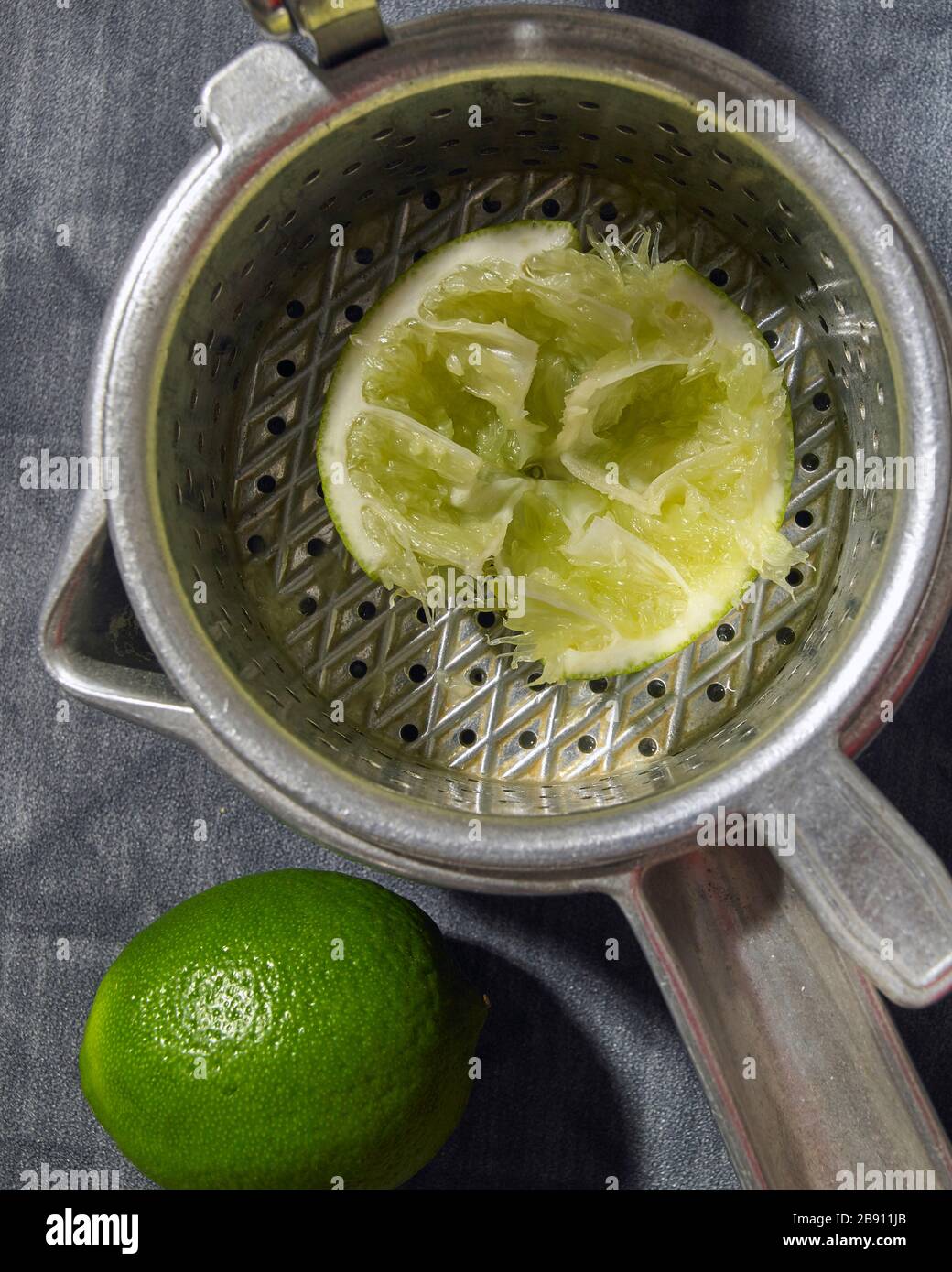 Fresh lime squeezed in manual fruit juicer Stock Photo