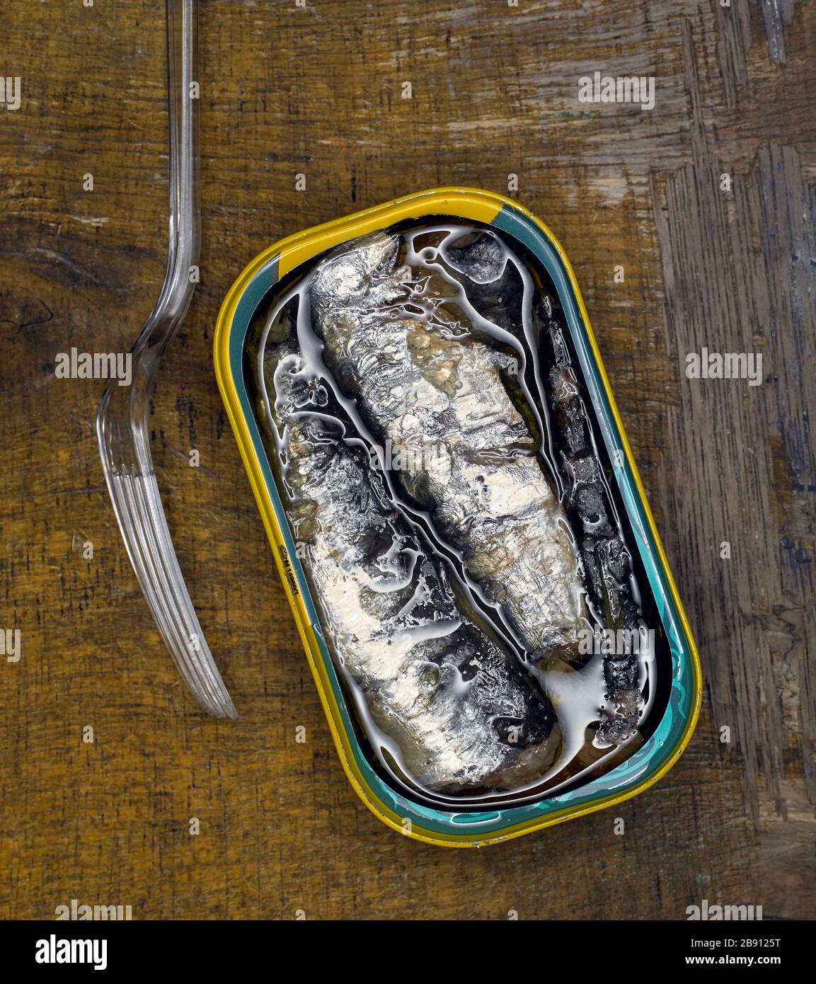 Open tin of sardines with a perspex fork shot from above Stock Photo