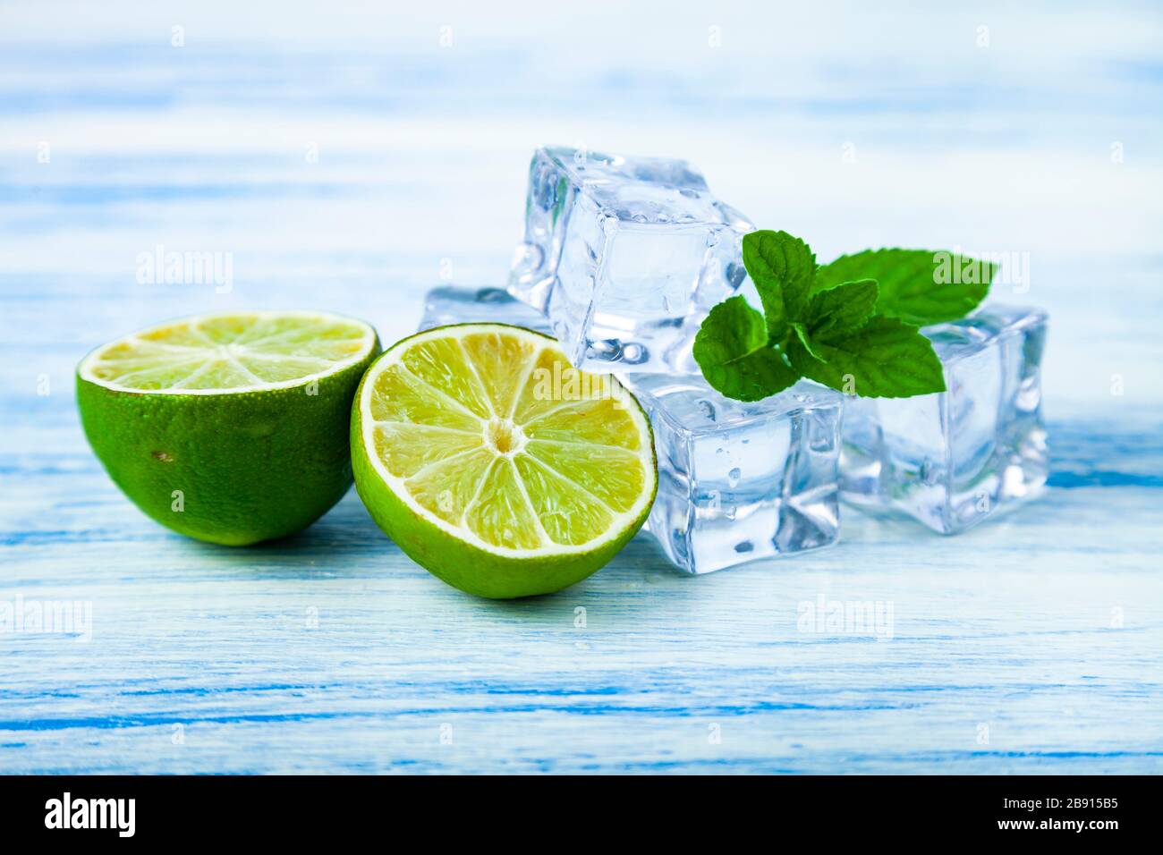 Lime, ice and mint on a blue wooden table. Stock Photo