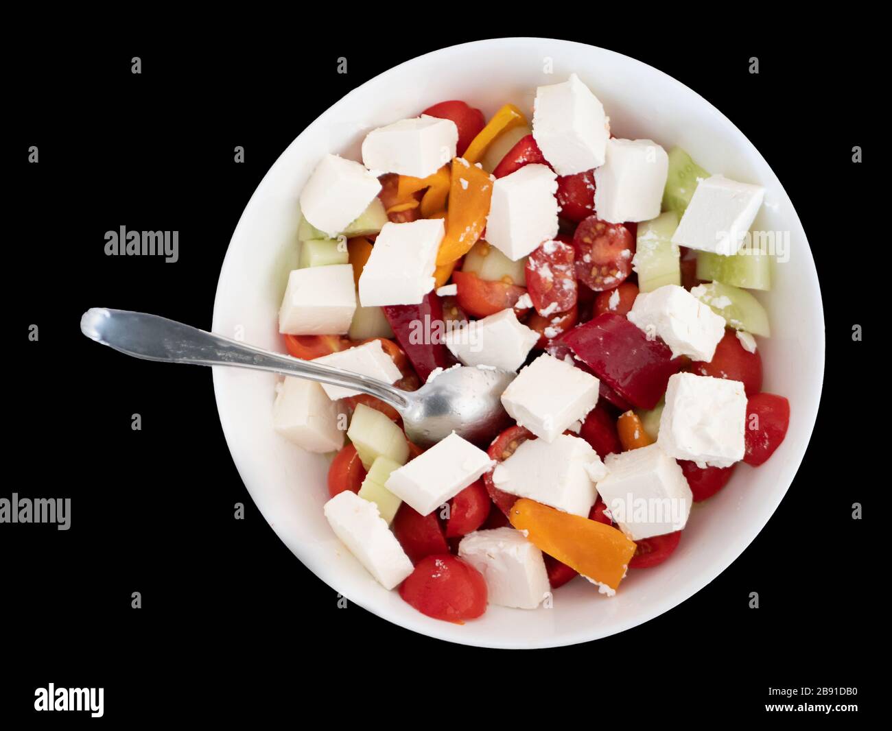 white bowl of greek salad isolated cutout on black bakground. red tomatoes, feta cheese, cucumbers, bulgarian pepper. Stock Photo