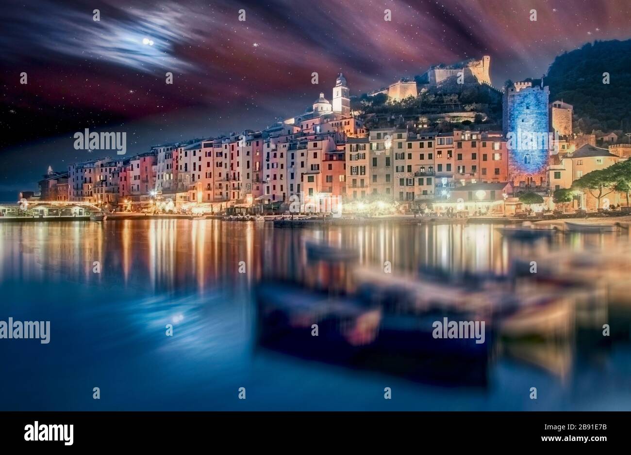 Portovenere, Italian Riviera, Liguria, Italy at sunset in a long exposure with a view past fishing boats of the colorful waterfront and Castello Doria Stock Photo