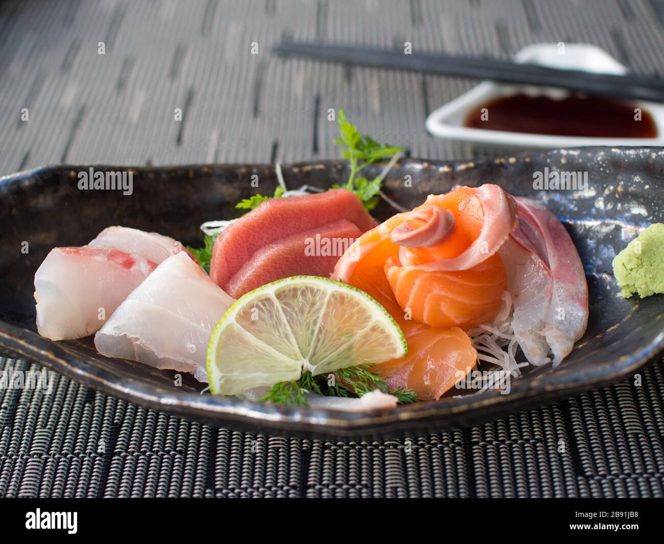 Japanese raw fish on black plate. Also known as Sashimi Stock Photo - Alamy