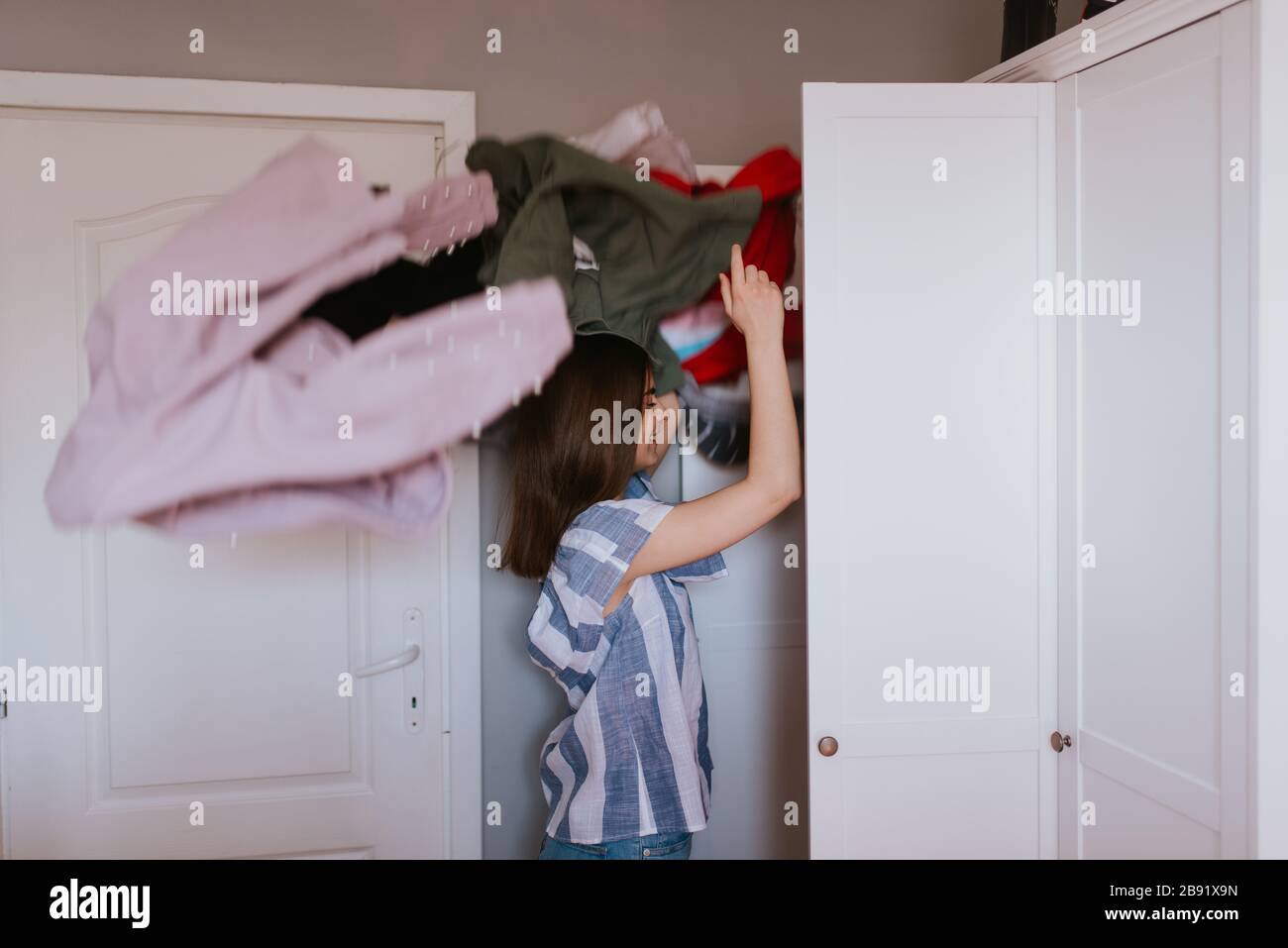 A teenage girl throws clothes out of her closet Stock Photo Alamy