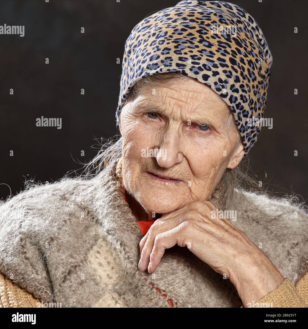 Studio portrait of old woman on dark background with intent look. People of such ages are most vulnerable during epidemics. Stock Photo
