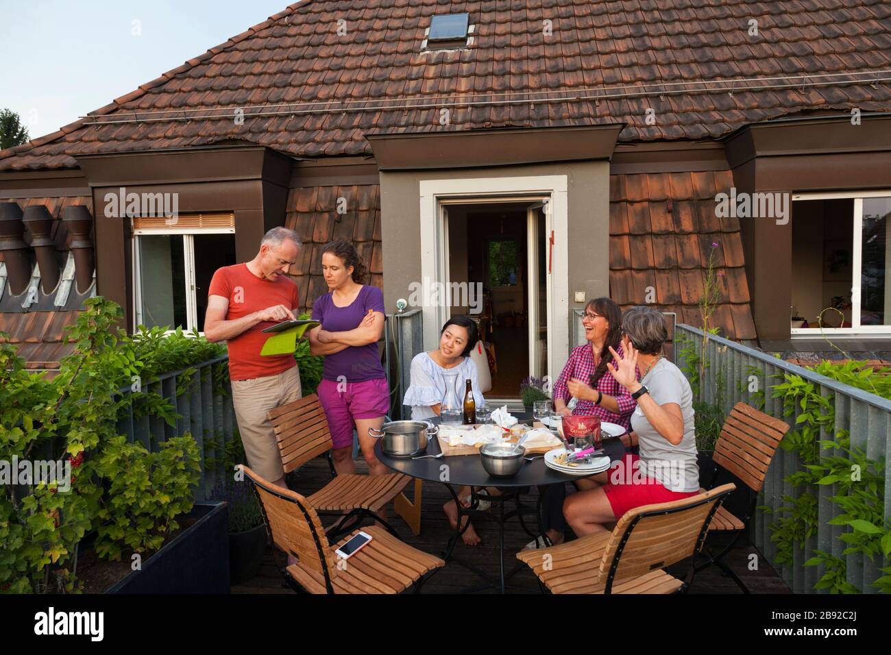 People eat dinner and chat on an apartment balcony in the Unterstrass neighborhood of Zürich, Switzerland. Stock Photo