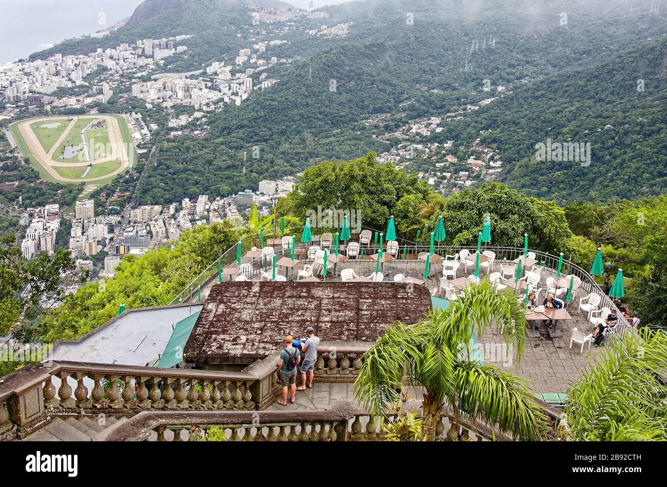 city overview, from Corcovado Mountain; foggy; outdoor restaurant, tables, chairs, stone steps, people, distant buildings, vegetation, South America; Stock Photo