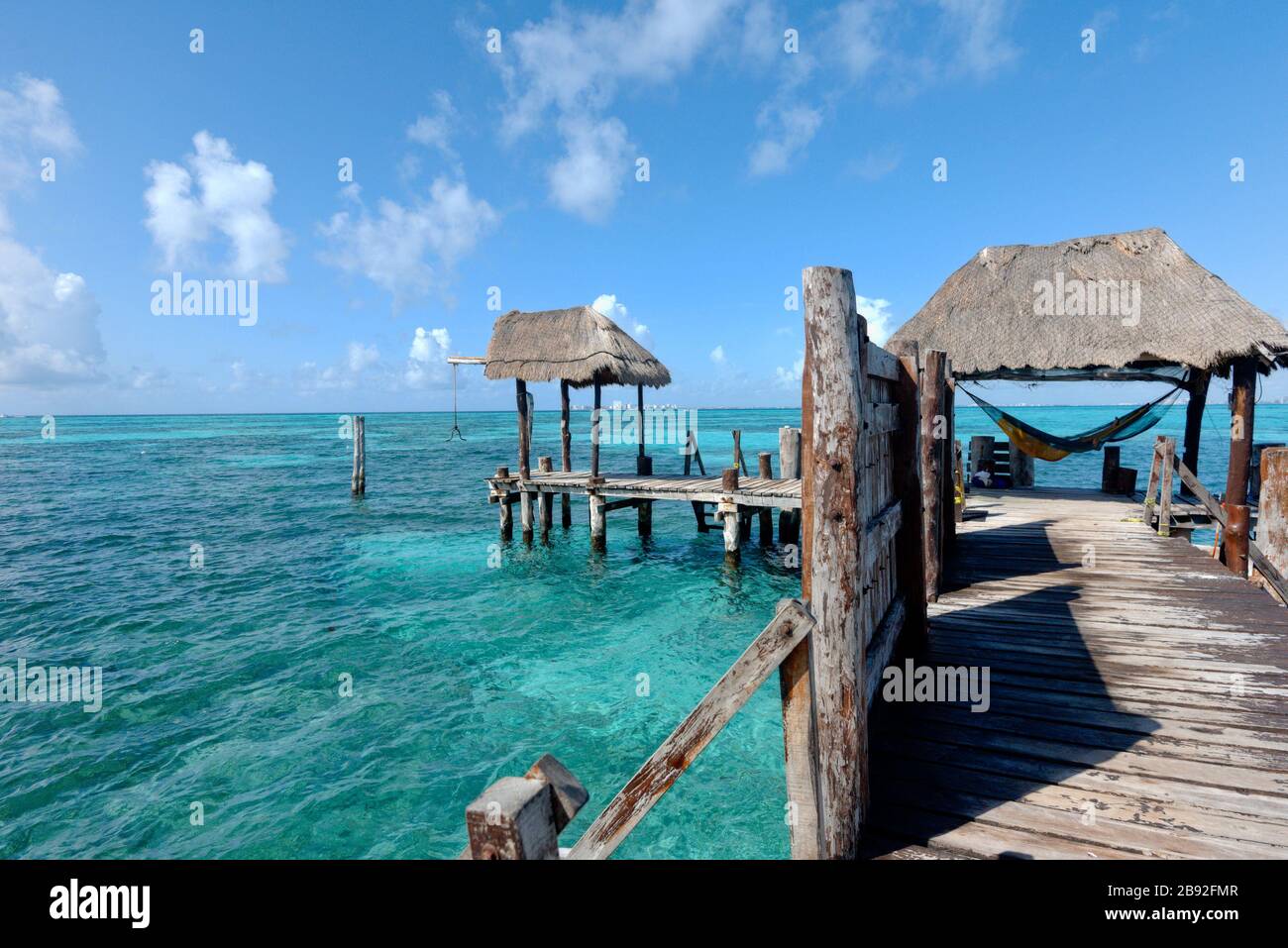 Wooden pier on the Caribbean sea, tourist relaxes in a hammock Stock Photo