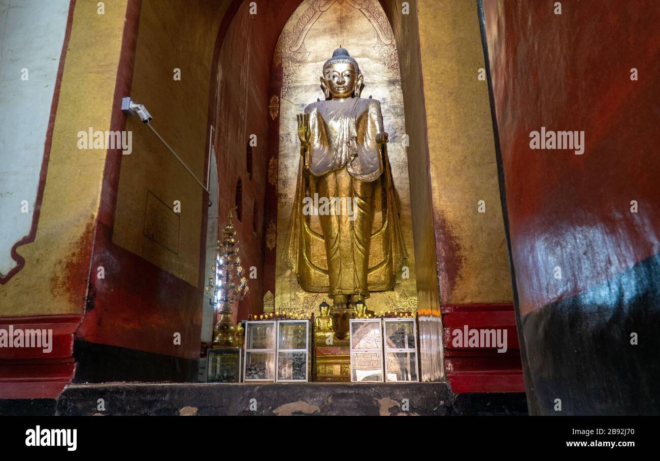 Buddha Statue inside Ananda Temple in Bagan, Myanmar. Placing gold leaf ...