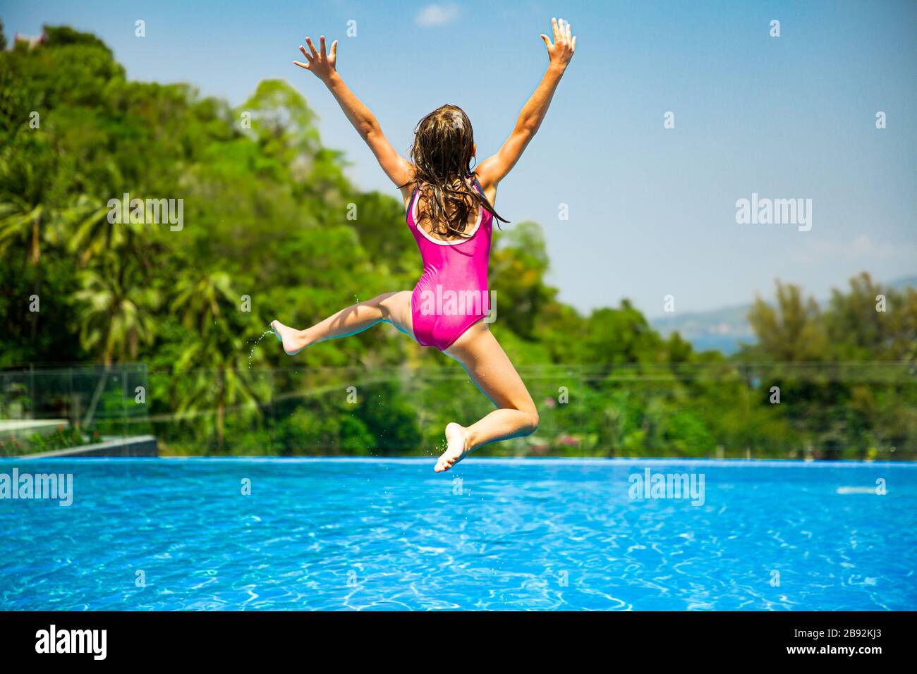 Excited funny little girl jumping to the swimming pool. Happy summer