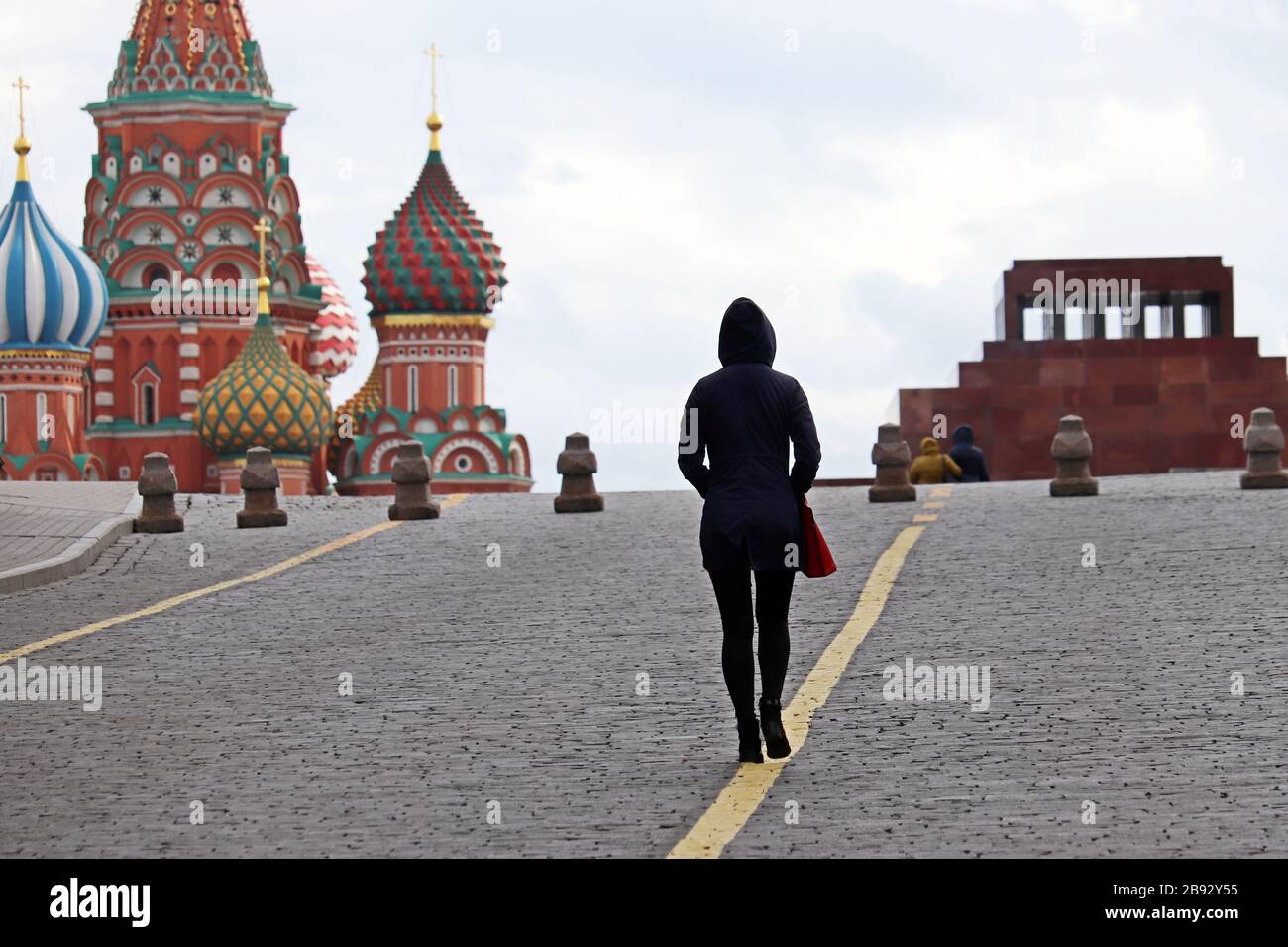Alone girl tourist walking on Red square in Moscow on background of St. Basil's Cathedral, selective focus. Empty streets during coronavirus pandemic Stock Photo