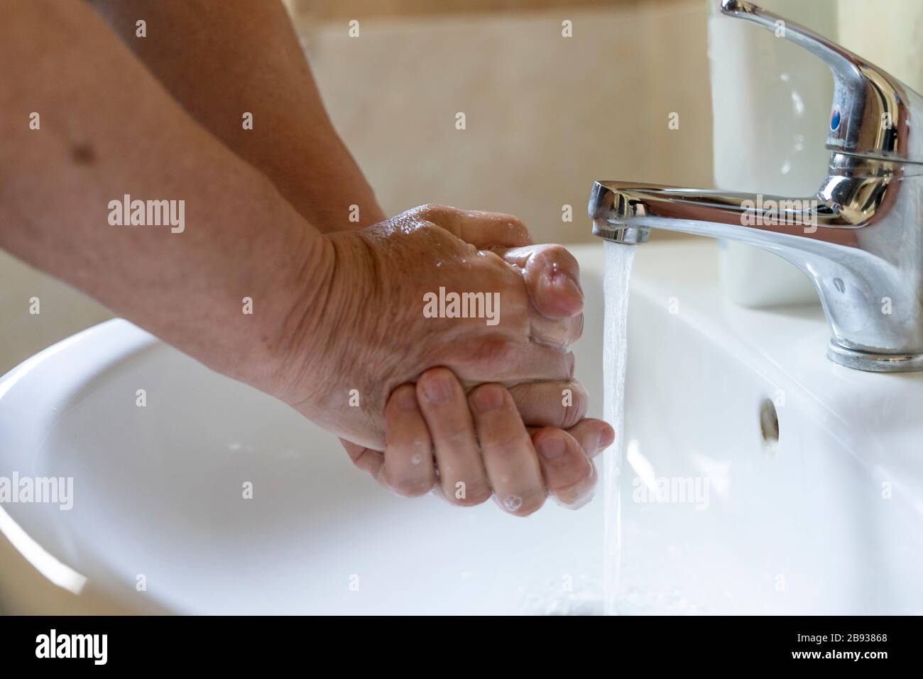 a man is washing his hands with antibacterial soap with running water ...