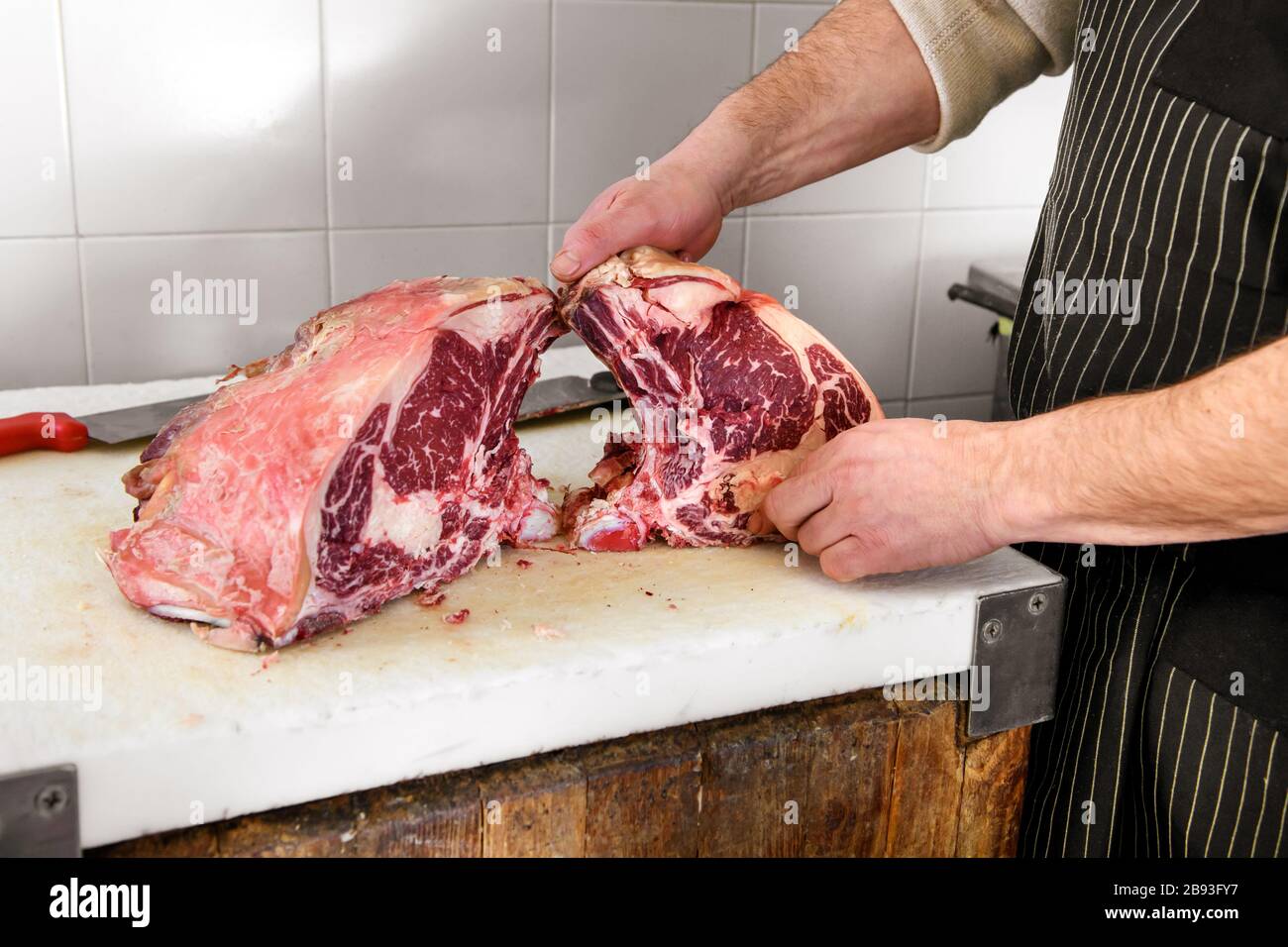 Butcher showing pieces of raw rib eye ham meat on cutting board Stock Photo