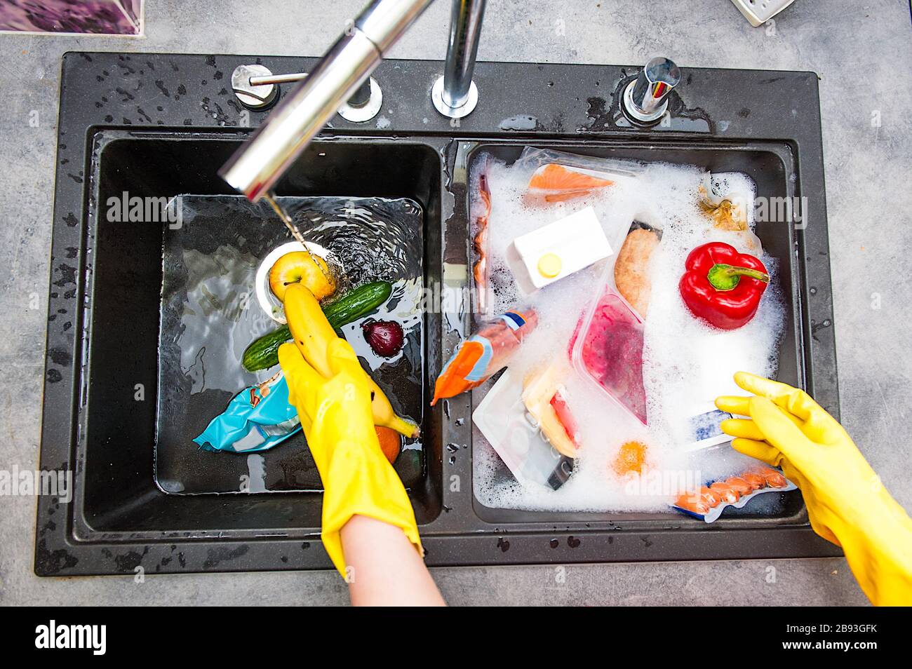 hands in yellow gloves are washing food products to get rid of bacteria