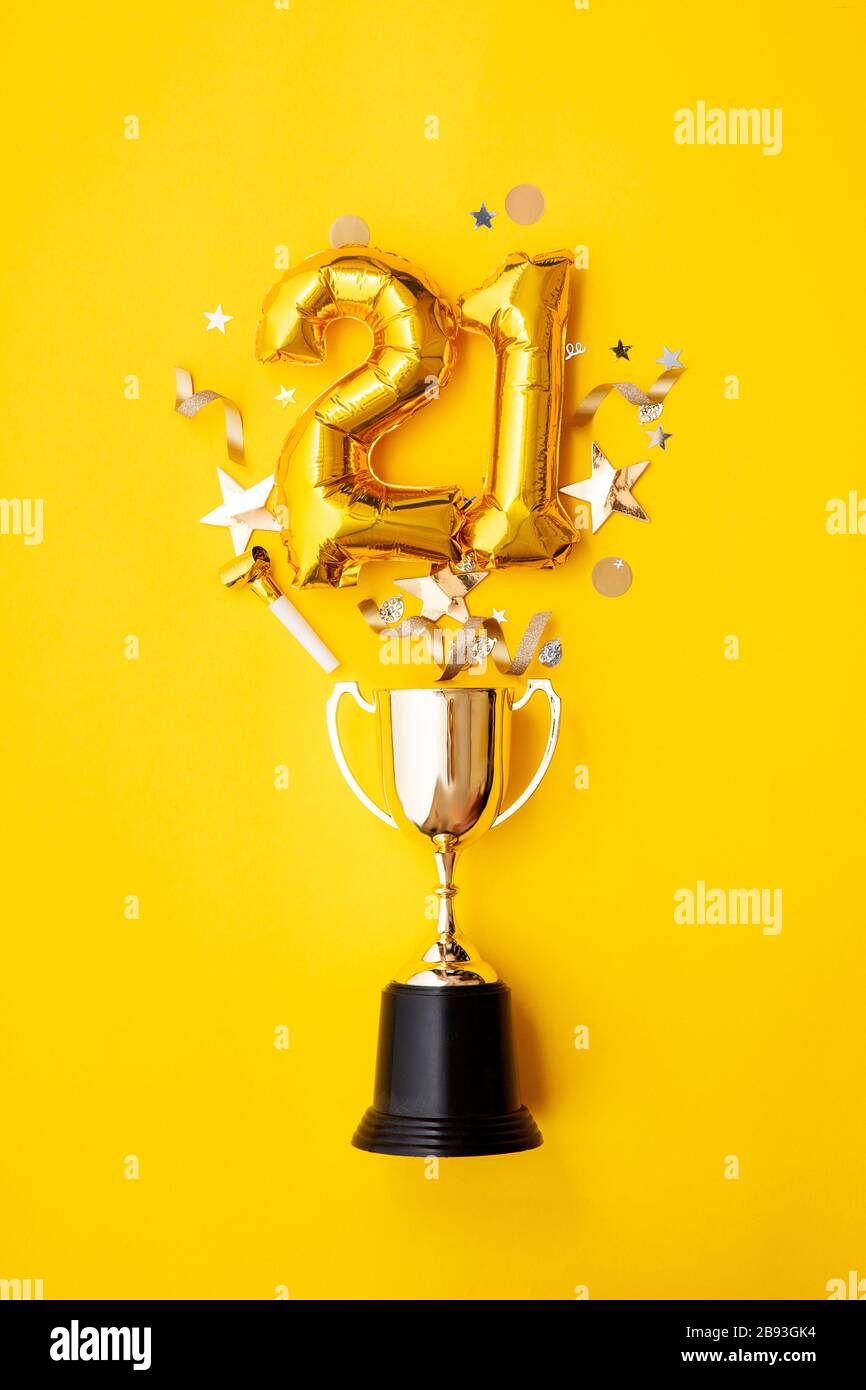 Number 21 gold anniversary celebration balloon exploding from a winning trophy Stock Photo