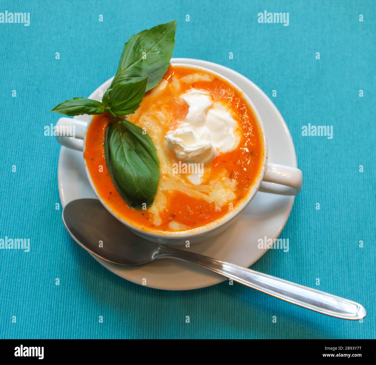 Tomato cream soup hot red color close up view on bright blue background. Selective focus. Copy space Stock Photo