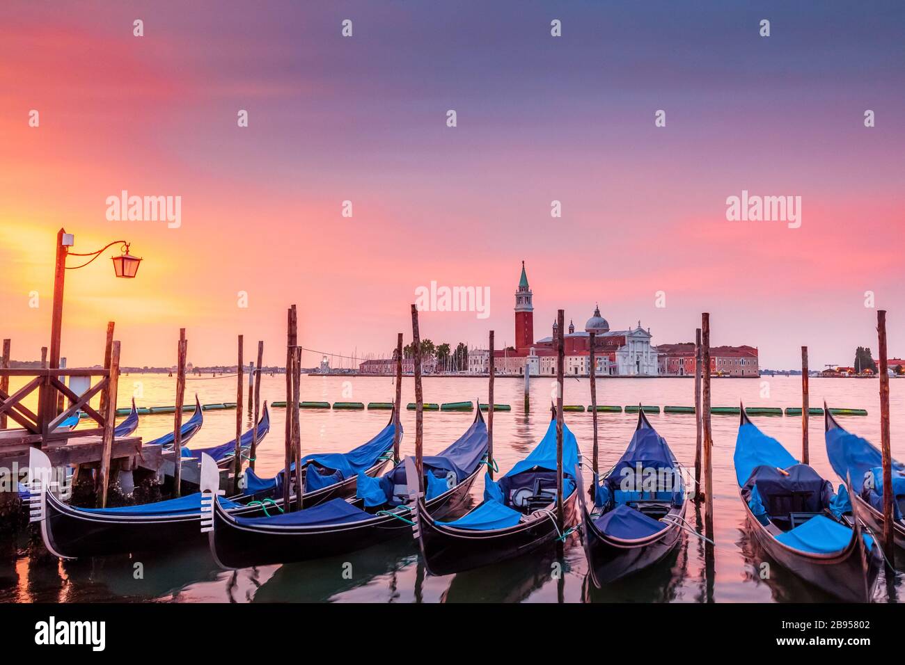 Dawn over the Grand Canal seen from St. Mark's Square in Venice, Italy.  Seen in the foreground are parked gondolas and in back is San Giorgio island Stock Photo