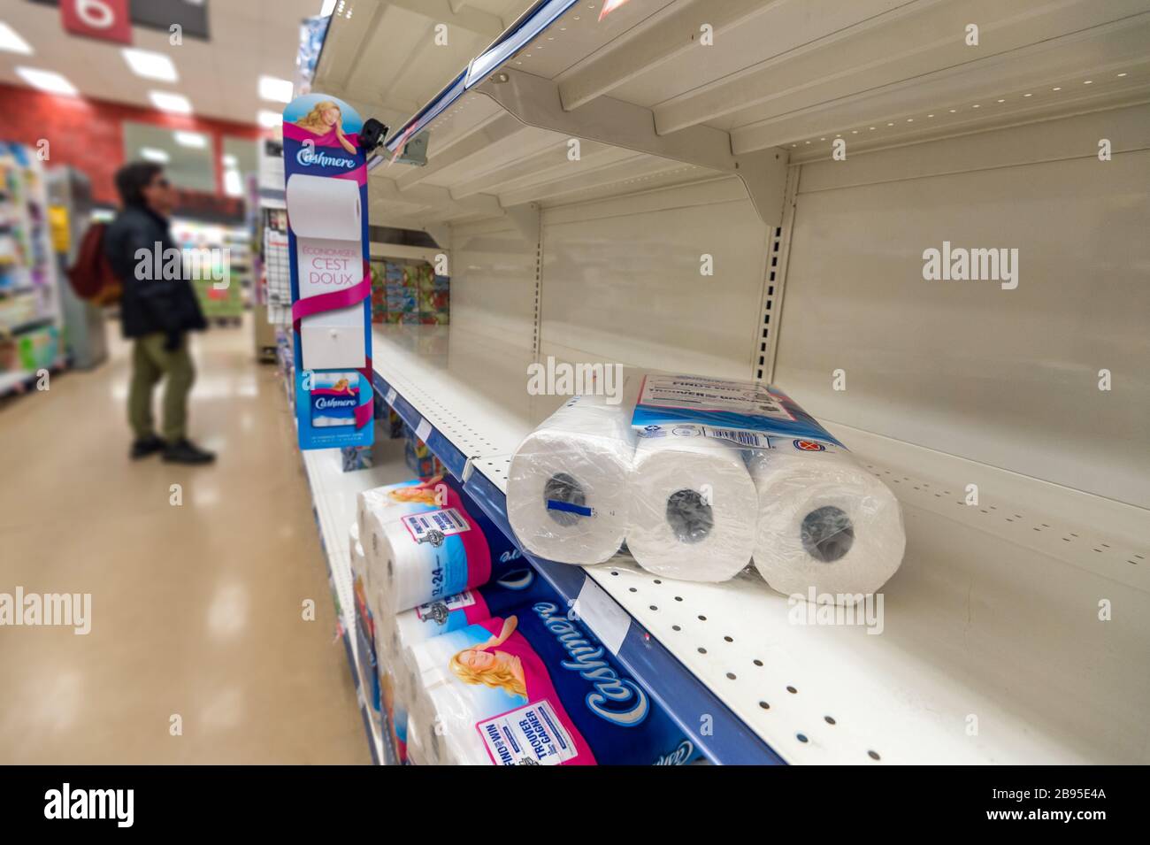 Montreal, CA - 20 March 2020: Empty shelves of toilet paper in a supermarket. Shortage of supplies due to panic of Coronavirus. Stock Photo