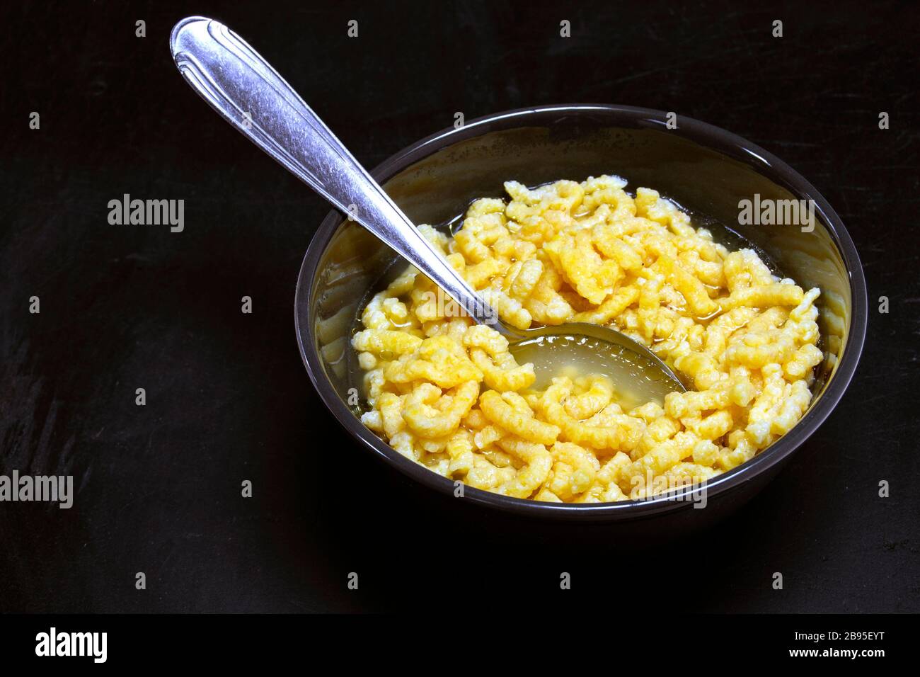 traditional italian pasta in broth passatelli, with black ceramic bowl