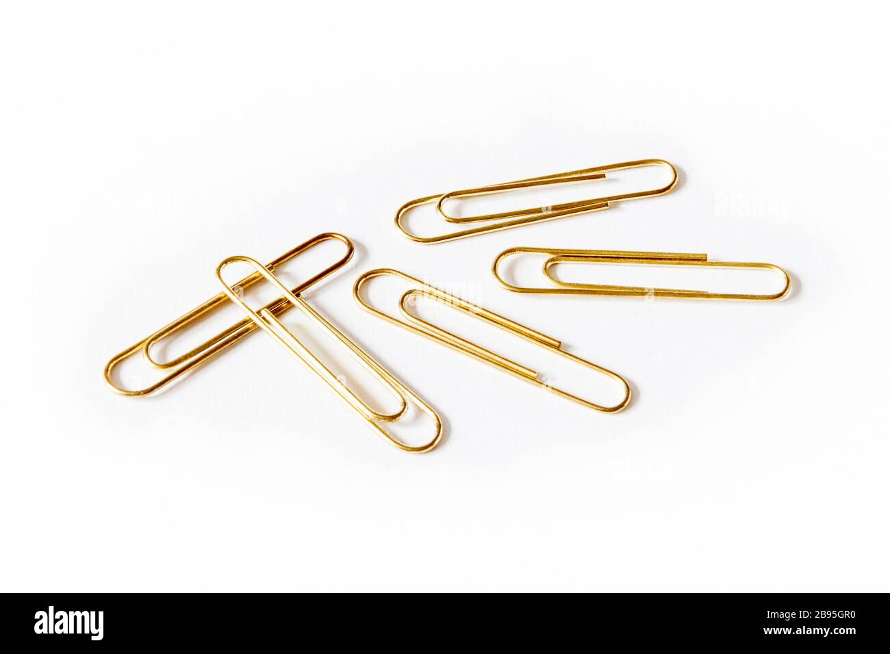 Five large gold-coloured paper clips on a white background Stock Photo