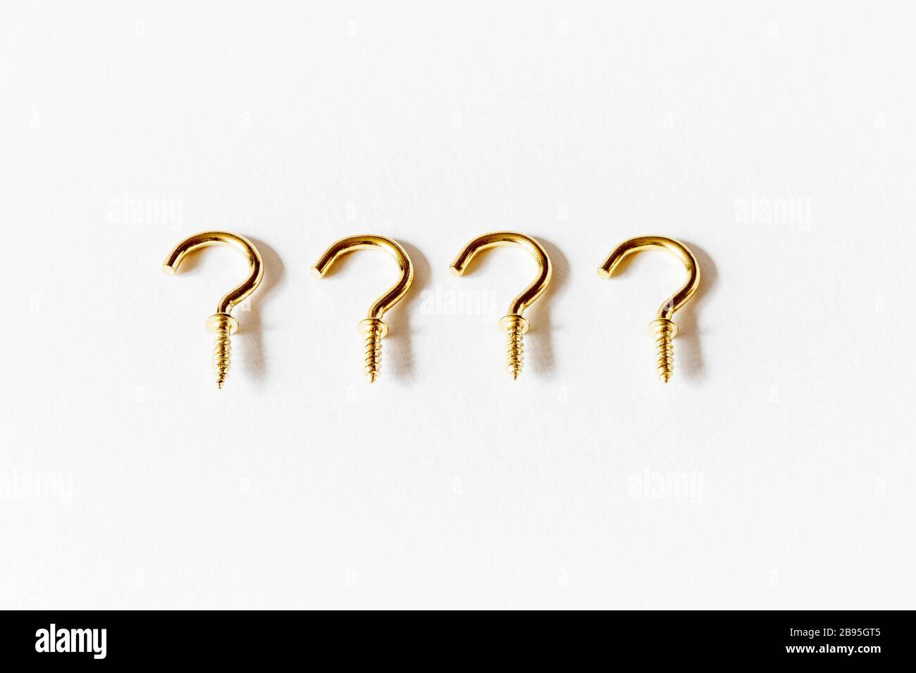 A horizontal line of four goldcoloured brass screw hooks on a white background Stock Photo Alamy