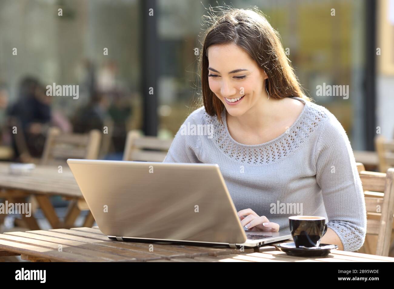 Happy young woman using laptop in a coffee shop terrace Stock Photo - Alamy