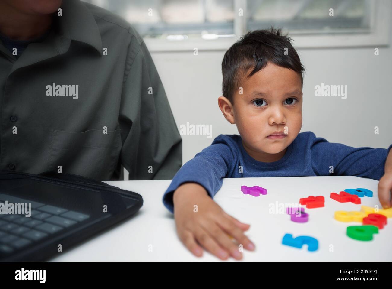 A preschooler displaying learning difficulties in a home setting where he is being evaluated to identify learning disorders. Stock Photo