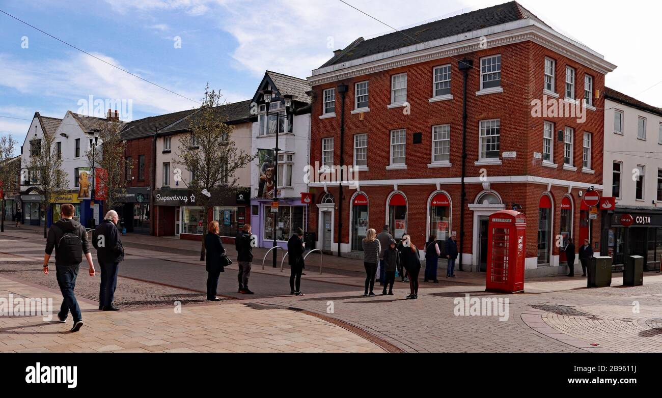 Customers queue outside the Santander bank in Ormskirk town centre.  Access to the bank was limited to one customer at once because of coronavirus. Stock Photo