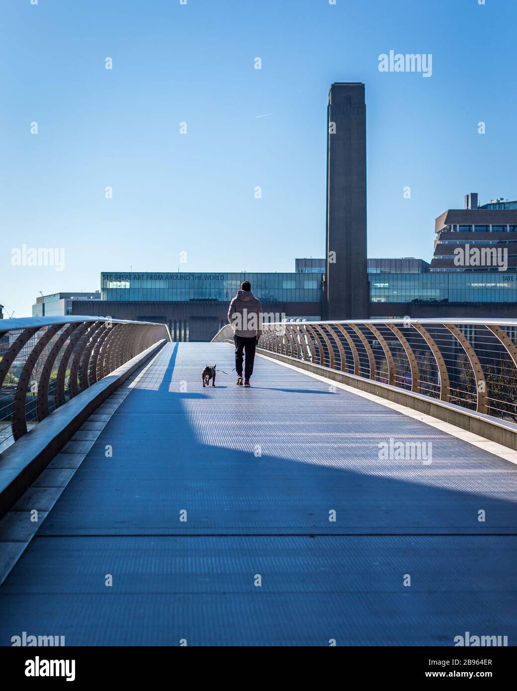 London, England - March 23, 2020: A lone walker & dog on millennium bridge in deserted London under lockdown during the Corona Virus Covid19 outbreak. Stock Photo