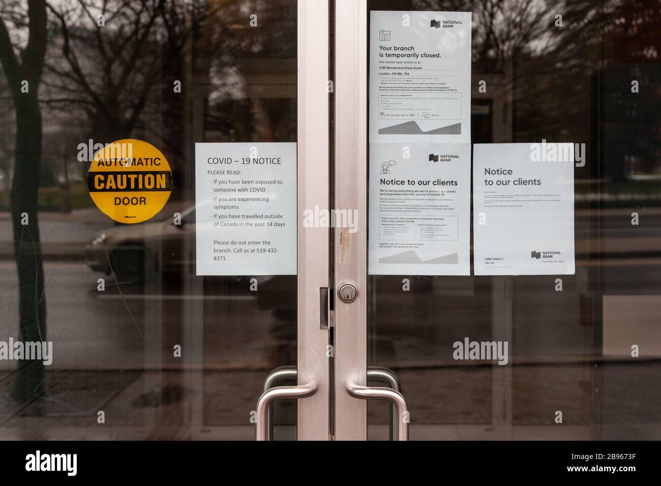 Notices on the doors of a bank branch in downtown London, Ontario, Canada informs customers the branch is closed due to COVID19 Pandemic. Stock Photo