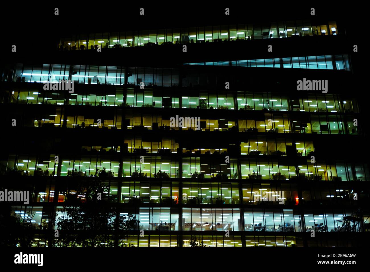 Colorful windows illuminated in a contemporary commercial building at night. Stock Photo