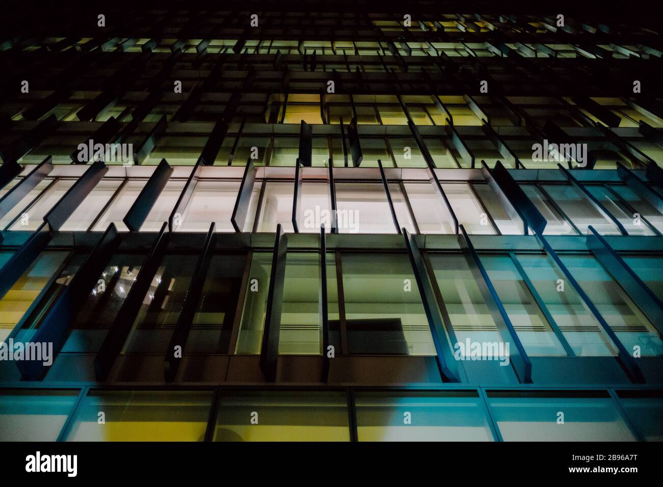 Colorful windows illuminated in a contemporary commercial building at night. Stock Photo