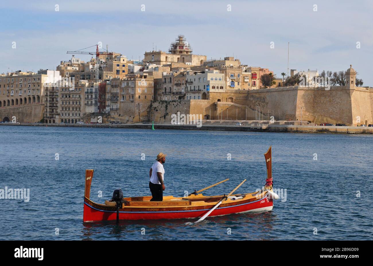 A man aboard a traditional Maltese water taxi, called a dgħajsa, in the Grand Harbour near Senglea, one of the Three Cities. Stock Photo