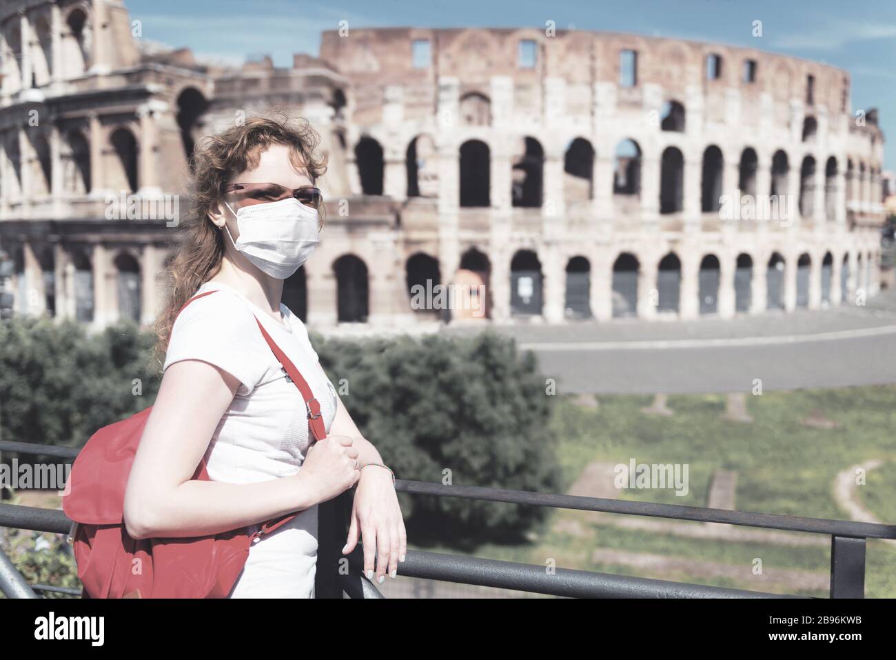 COVID-19 coronavirus in Italy, woman in face medical mask next to empty Colosseum in Rome. Tourist landmarks closed due to corona virus outbreak. Stock Photo