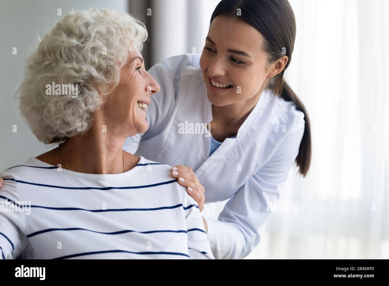 Caring young nurse assist handicapped mature female patient Stock Photo