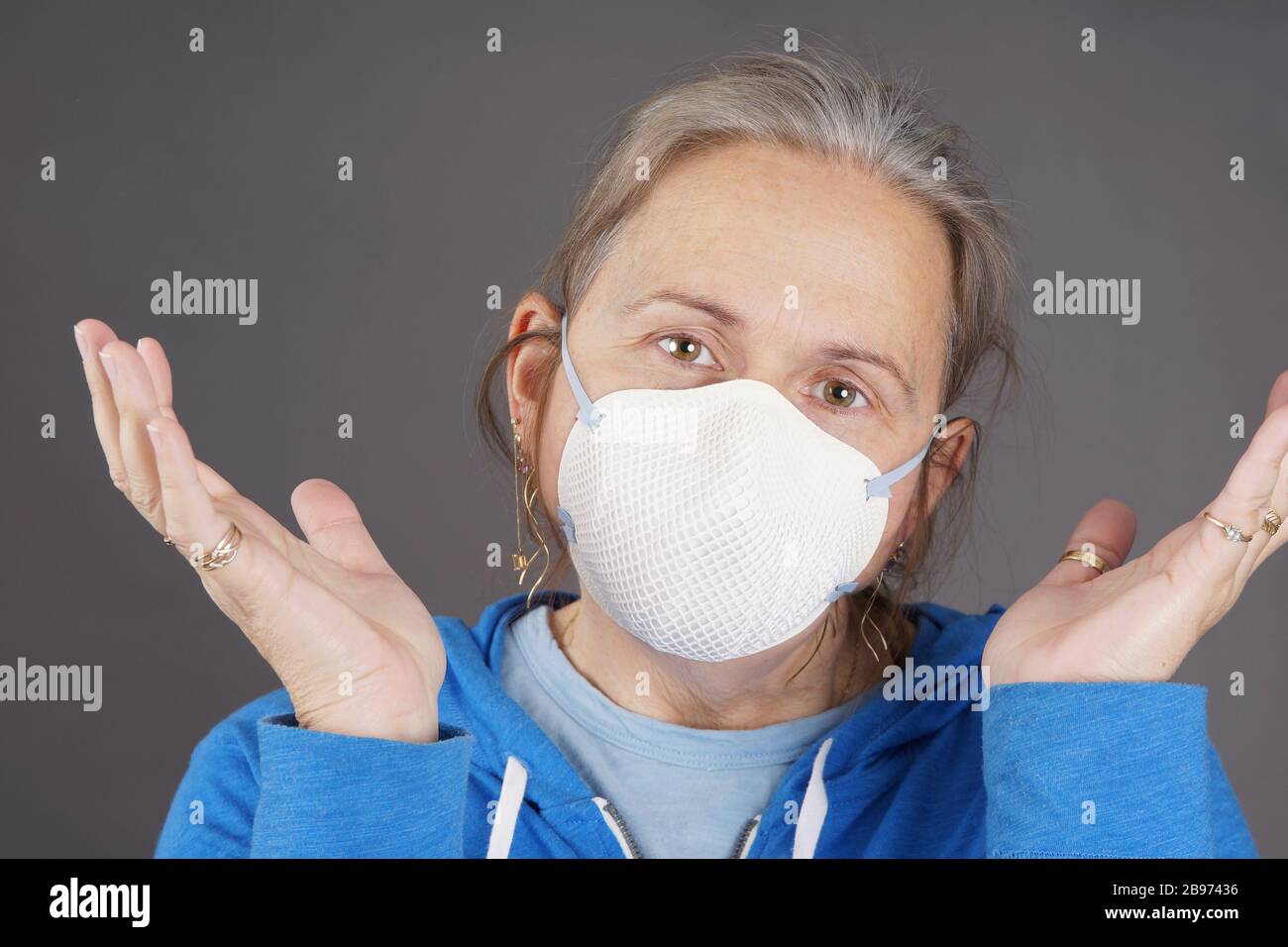 Woman with mask raising hands coping with pandemic coronavirus COVID-19 Stock Photo