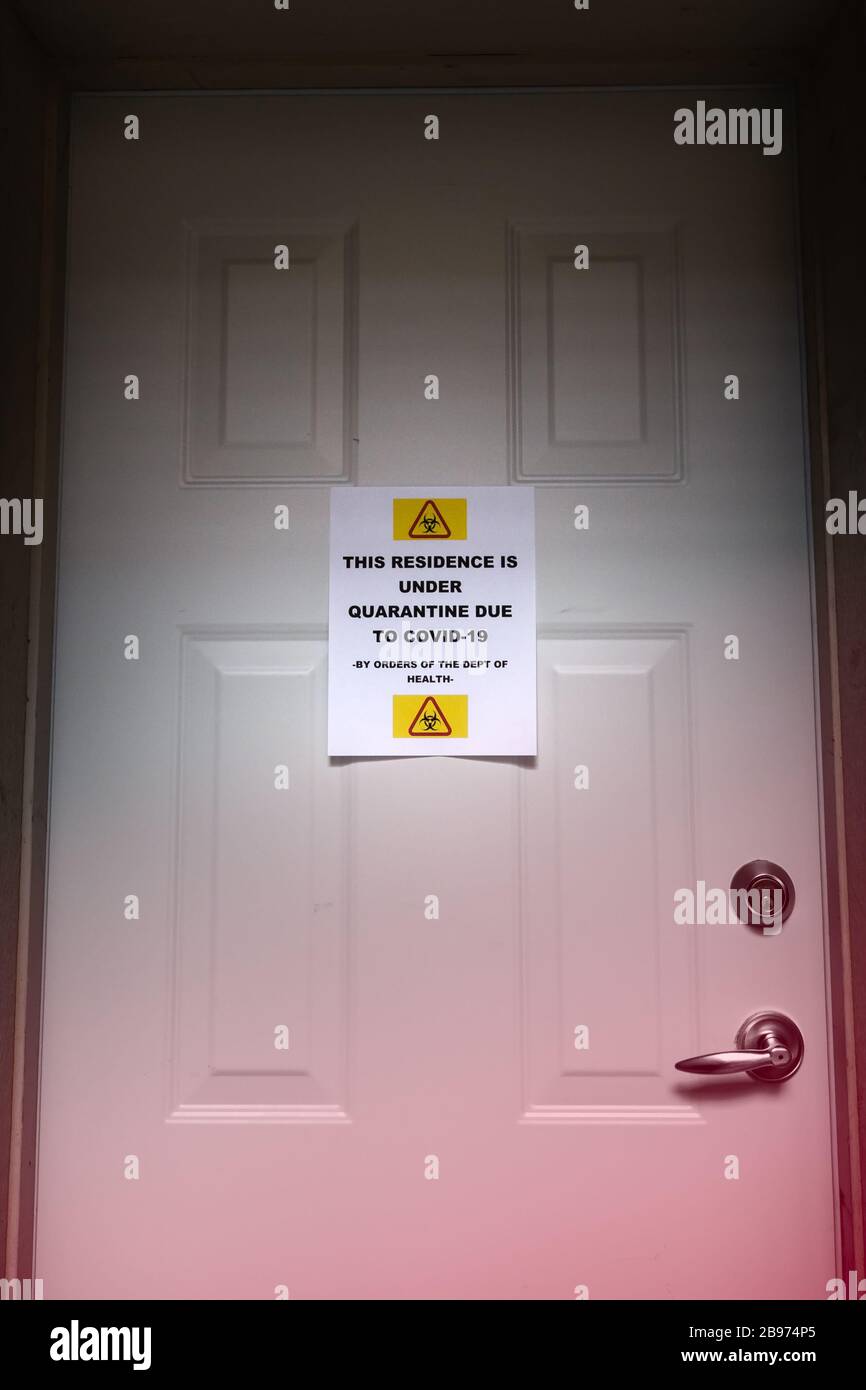 A self isolating residence with a quarantine sign on the front door warning of the Covid-19 virus. Stock Photo