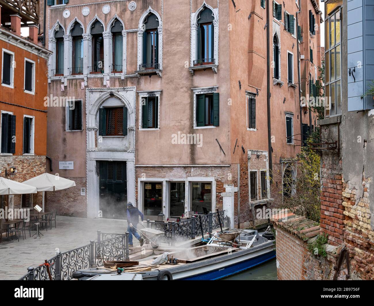 Construction site rubble is brought onto a boat with a small wheelbarrow, Venice, Veneto, Italy Stock Photo