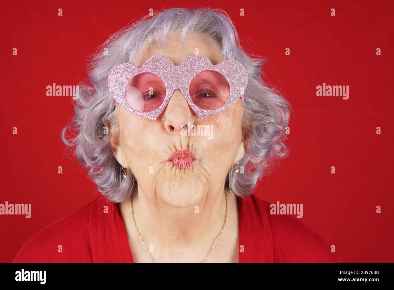 Comical granny with heart shape glasses blowing kiss Stock Photo