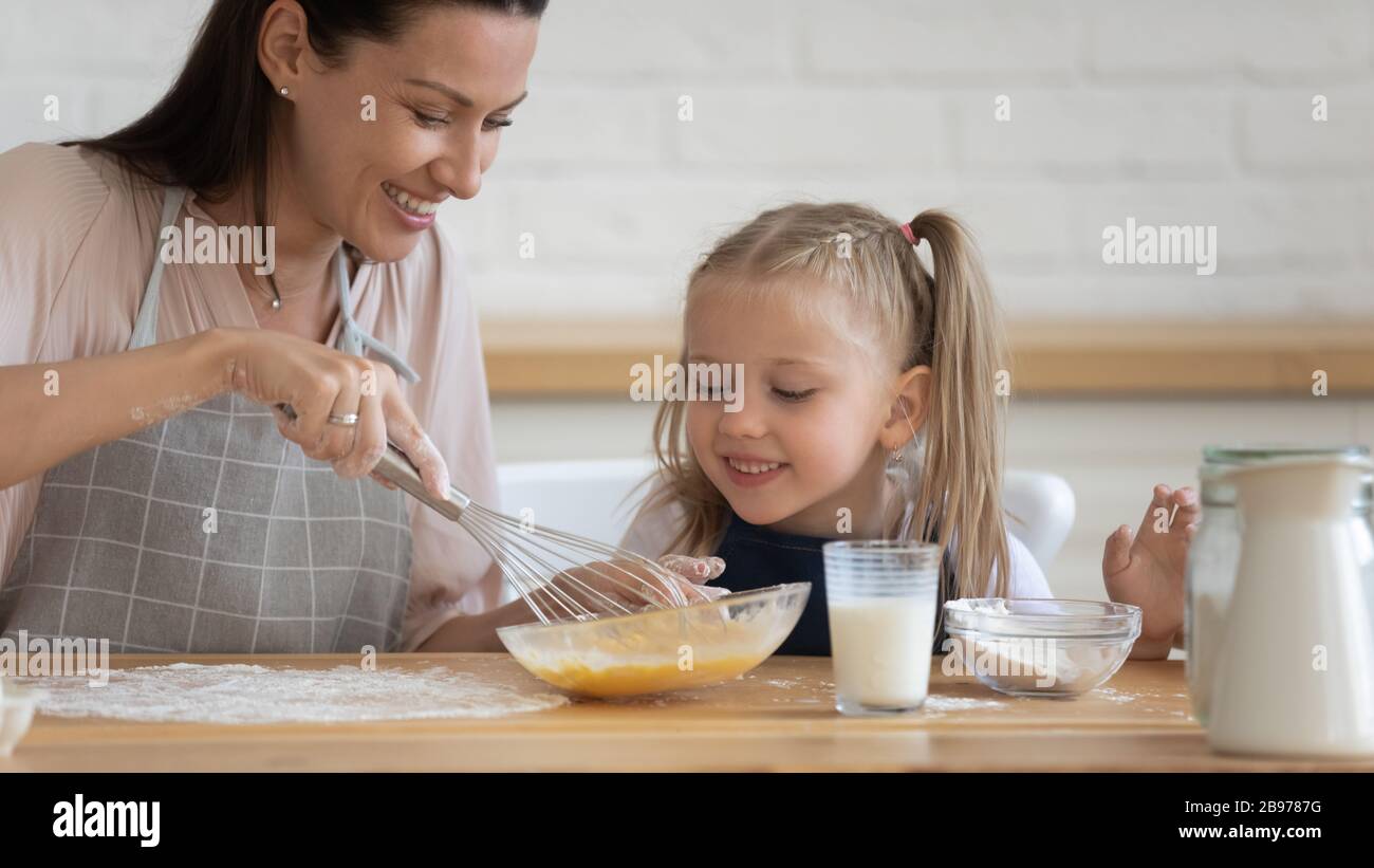 Happy mom and daughter cooking pancakes together Stock Photo